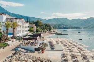 een strand met parasols en boten in het water bij Hotel Perla in Herceg-Novi