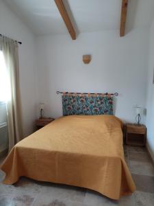 a bedroom with a large bed with a yellow blanket at maison grysélienne in Gréoux-les-Bains