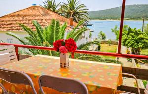 einen Tisch mit einer Vase mit einer roten Blume darauf in der Unterkunft Amazing Apartment In Otok Ist With Wifi And 2 Bedrooms in Ist