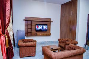 a living room with two chairs and a flat screen tv at CRISPAN SUITES & EVENT CENTRE in Jos +27 photos