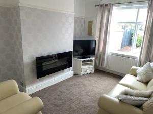 sala de estar con TV de pantalla plana y sofá en Croyden villa en Blackpool