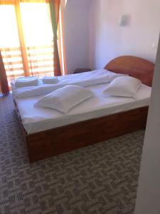 łóżko z białą pościelą i poduszkami w sypialni w obiekcie Valea lui Bogdan w mieście Moieciu de Jos