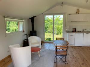 uma cozinha com cadeiras brancas e uma mesa em Le Chalet dans la Nature em Saulcy-sur-Meurthe