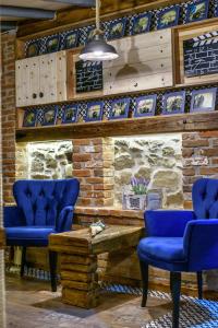 a room with blue chairs and a stone wall at Traditional Guesthouse in Tríkala