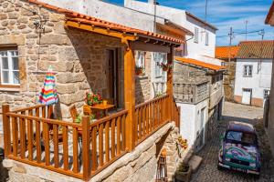 een stenen huis met een houten balkon en een auto bij Casa do Chefe in Videmonte