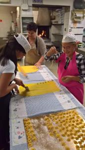 Eine Gruppe von Frauen steht in einer Küche und bereitet Lebensmittel zu in der Unterkunft Azienda Agrituristica Piccolo Ranch in San Pietro