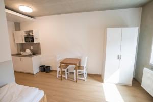 ein Zimmer mit Tisch und Stühlen und eine Küche in der Unterkunft SITE.INN Denkendorf in Denkendorf