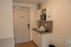 una pequeña cocina blanca con microondas y encimera en SITE.INN Denkendorf en Denkendorf