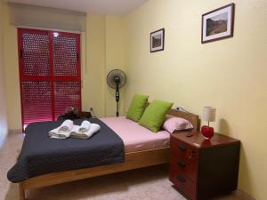 a bedroom with a bed with green pillows and shoes on it at ROMI CENTRO tu Alojamiento en TEULADA in Teulada