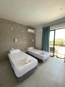 a hotel room with two beds and a balcony at Ikaros Studios in Faliraki