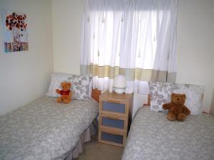 two teddy bears sitting on two beds in a bedroom at Bend in the River Lodge in Stratford-upon-Avon