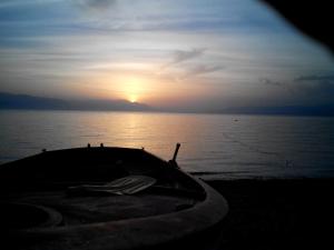 un barco en la playa con la puesta de sol en el fondo en Tina Rooms, en Gialtra