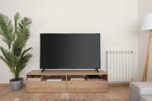 VIGO THE HOME في فيغو: تلفزيون بشاشة مسطحة على منصة خشبية في غرفة المعيشة