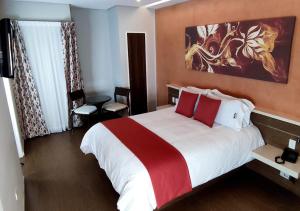a bedroom with a large bed with red and white pillows at Novo Hotel in Caracas