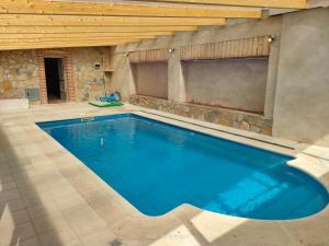 - une grande piscine dans une maison dotée d'un mur en pierre dans l'établissement Casa Rural Baños del Rey con piscina climatizada, à Vega de Santa María