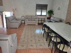 ein Wohnzimmer mit Sofas und einem Tisch und Stühlen in der Unterkunft Casa Rural Baños del Rey con piscina climatizada in Vega de Santa María
