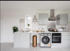 a kitchen with a washing machine and a stove at Penthouse Luxury Apartment in Dagenham