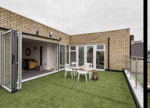a patio with a table and chairs on the grass at Penthouse Luxury Apartment in Dagenham