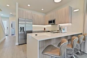 a kitchen with a large island with chairs and a refrigerator at New Spacious&Tranquil Townhouse near Disney in Orlando