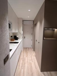 a small kitchen with white cabinets and a refrigerator at Cap Salou Apolo in Salou