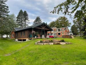 a log house on a green field with a yard at Beach Cottage Inn in Lincolnville