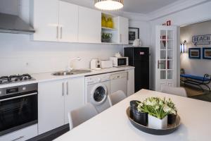 uma cozinha com armários brancos e uma mesa com plantas em Casa "Vó Minda" - Nazaré - Alojamento Local na Nazaré
