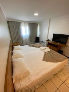 een groot wit bed in een kamer met een bureau bij Ponta Negra Flat ByHotéis in Natal