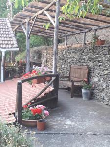 un patio con un banco y flores y una pared de piedra en La casetta, en Varazze