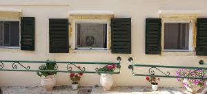 a building with shuttered windows and flowers on it at Spianada Collection of Studios & Apartments by Konnect in Corfu Town