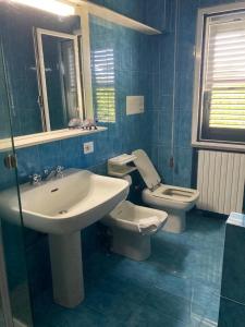 een blauwe badkamer met een wastafel en een toilet bij Appartamenti Podere 270 in Punta Ala