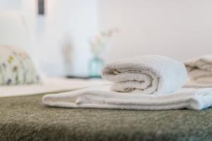 een stapel handdoeken bovenop een bed bij Casas Barulho - Villa Jacaranda A8 in Albufeira +40 foto's