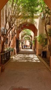un vicolo con un arco con alberi in città di Riad Syrine a Marrakech