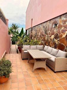 a patio with a couch and a wooden table at lujosa villa con piscina privada in Puerto de la Cruz