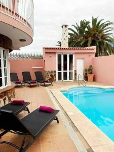 プエルト・デ・ラ・クルスにあるlujosa villa con piscina privadaのリゾートの建物の隣にスイミングプールと椅子があります。
