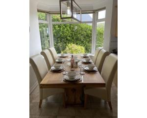 mesa de comedor con sillas blancas y ventana en Lower Upover, en Woolacombe