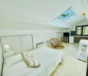 a white bedroom with a bed and a kitchen at Studio mansardé climatisé les roseaux bord de lac in Biscarrosse