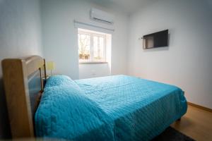een slaapkamer met een blauw bed en een raam bij Casa Rural "A Escola" - Meãs, Pampilhosa da Serra in Pampilhosa da Serra