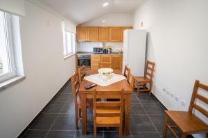 a kitchen with a table and chairs and a refrigerator at Casa Rural "A Escola" - Meãs, Pampilhosa da Serra in Pampilhosa da Serra