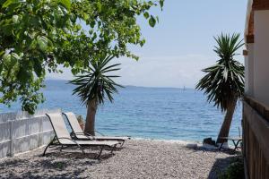 Una silla blanca sentada en la playa cerca del agua en Salt & Sun Apartments by Konnect, at Kaminaki Beach en Nisaki