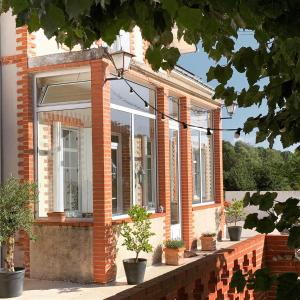 una casa de ladrillo con ventanas y macetas en La Grenouillère - Chambre d'hôtes de charme en Ballan-Miré
