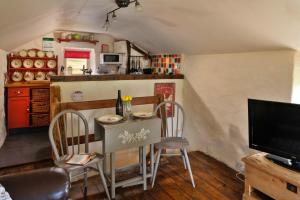 a small kitchen with a table and chairs and a television at Finest Retreats - Woodend - The Bothy in Ulpha