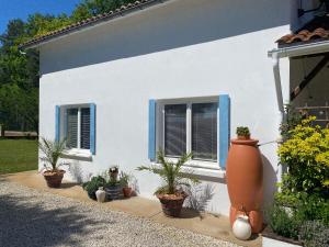 a white house with blue windows and potted plants at Gite Les Justices in Édon