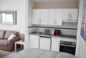 a kitchen with white cabinets and a glass table at Blue Ocean in Puerto del Carmen