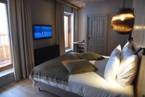 a bedroom with a bed with pillows and a television at Hotel MONT-BLANC VAL D'ISERE in Val dʼIsère