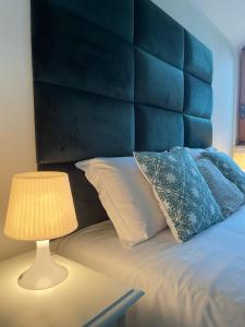 a bed with a blue headboard and a table with a lamp at Villa Martini dei Rossi in Sanfrè