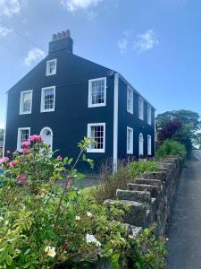 una casa blu con dei fiori davanti di Dovenby Apartment- great base for exploring Lake District a Cockermouth