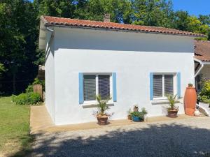 a white house with potted plants in front of it at Gite Les Justices in Édon