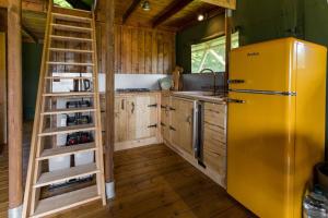 uma cozinha com um frigorífico amarelo e armários de madeira em Awe Inspiring two storey tent em Crowhurst