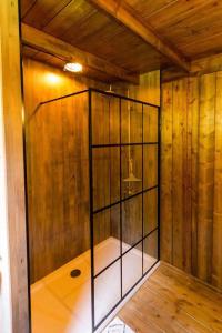 a shower in a room with wooden walls and wood floors at Awe Inspiring two storey tent in Crowhurst