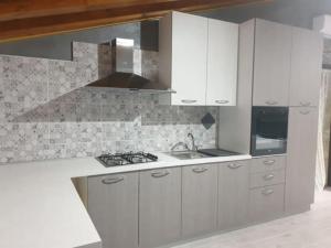 - une cuisine avec des placards blancs et une cuisinière dans l'établissement Casa Nettuno in Villa Marisa, à Borgo Bonsignore